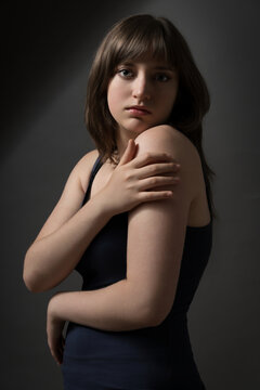 Portrait of a beautiful teenage girl posing on dark background
