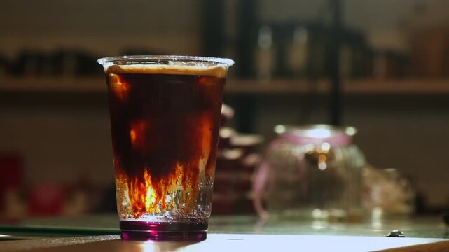 Freshly poured coffee forms dramatic streams as mixes with ice and soda in cup closeup. Chilled drink offers bold and refreshing experience
