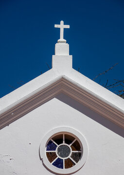 White chapel gable topped with a cross above a round stained-glass window, Huila Province, Lubango, Angola