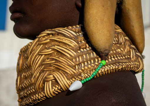 Profile close-up of a Mwila woman's ochre hair roll draped over a woven shoulder covering decorated with cowrie shells, Huila Province, Lubango, Angola