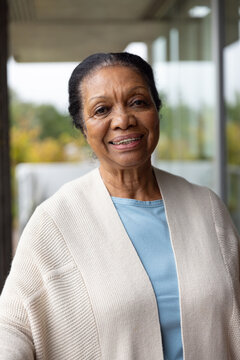Senior African American woman standing on patio wearing tan cardigan and blue top