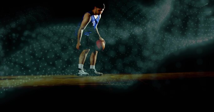 Dribbling male basketball player bending on hardwood court, blue jersey, socks, teal fog