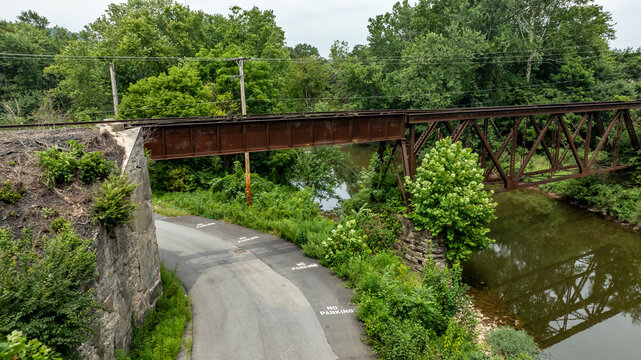 Bridge Crosses a Road Near a River Surrounded by Trees in a Rural Area on a Cloudy Day