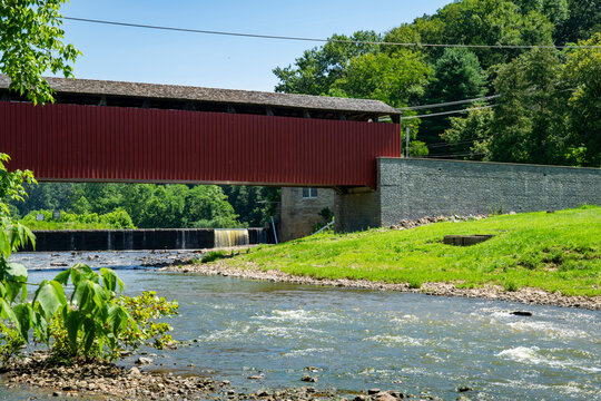Scenic View of a Red Covered Bridge Over a River in a Lush Green Landscape During Daytime