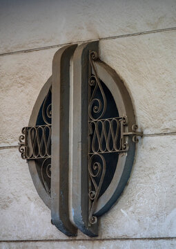 Oval wrought-iron ventilation grille with scrollwork decorates a weathered plaster wall, Luanda Province, Luanda, Angola