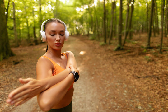 Young female athlete stretching her upper body on woodland trail before exercise