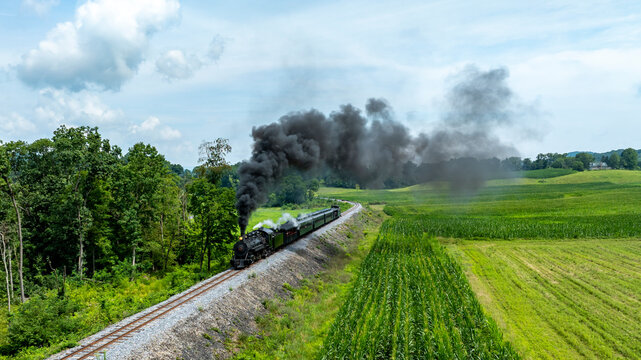 Steam Locomotive Travels Through Lush Countryside Under a Clear Blue Sky