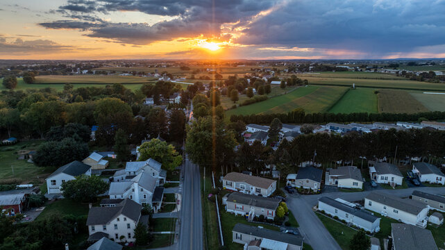 Sunset Above Houses and Fields With Scattered Clouds in the Sky