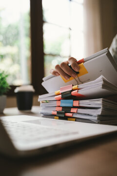 A close-up shot of an Asian woman handling a large volume of documents and files, dealing with organization, management, deadlines, workload, bureaucracy, and business responsibilities.