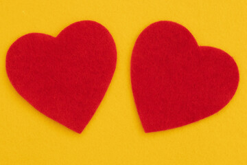 Fototapeta premium Two red hearts on bright yellow felt for romance