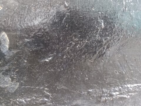 Glossy black textured surface with rough wet asphalt or dark metallic finish, ideal for abstract background design