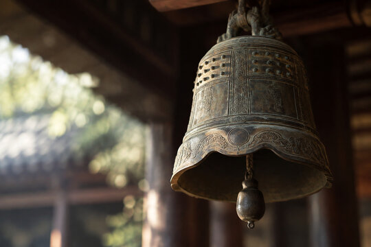 An ancient bronze bell with its clapper hanging still, textured metal surface in soft light.