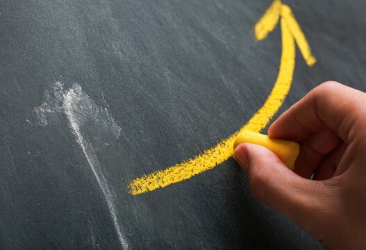 Yellow chalk arrow curves upward on dark textured surface