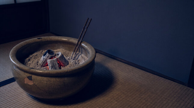 Japanese charcoal brazier with iron tongs on a tatami floor
