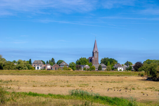 Small town villages in the border of North Brabant (Noord-Brabant) and Limburg provinces in Netherlands, Traditional houses and church under blue sky and white clouds in summer, Countryside in Holland