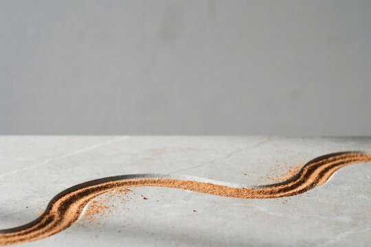 Copper coloured pigment tracing an s-curve across a grey stone surface