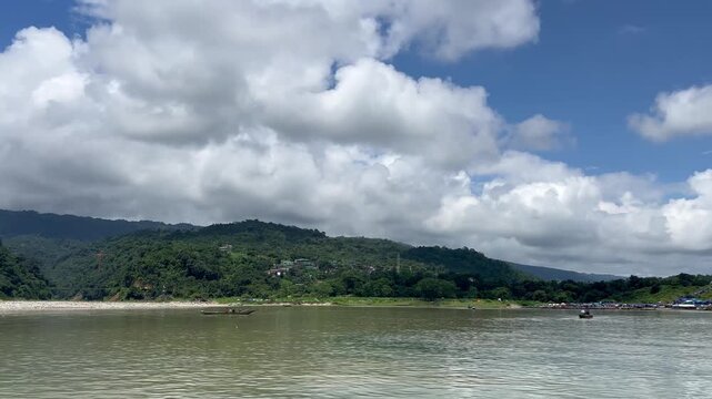 Jaflong Sylhet Small fishing boats drift on wide river under dramatic cloudy sky with green hills behind