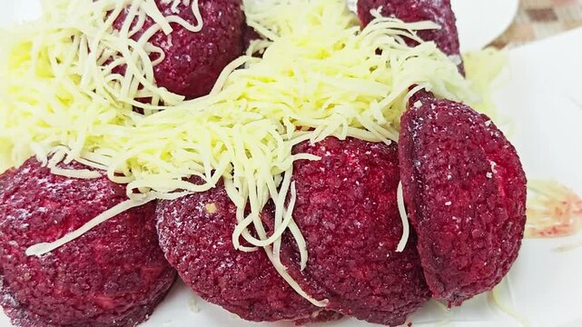 Red velvet chouquettes or choux pastry puffs topped with shredded cheese.