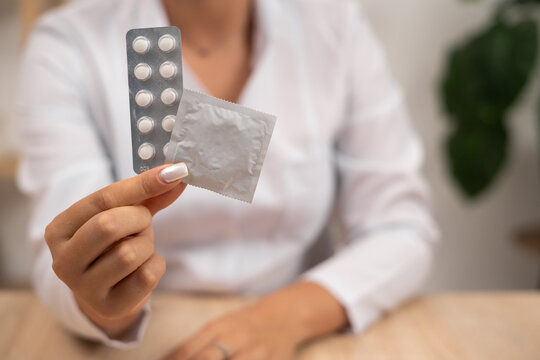 Female doctor holds pills and condom talks about methods of contraception. birth control and AIDS prevention