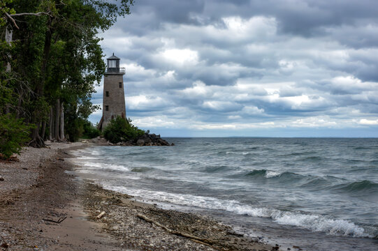 Captivating view of the historic lighthouse on Pelee Island, Ontario, with dramatic skies and a rocky shoreline, capturing the island's natural beauty.