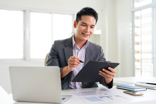 Young man in an office setting reviews documents attentively.