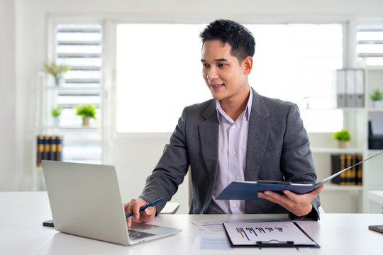 Confident young businessman auditing revenue report and planning budget while working at desk in office.