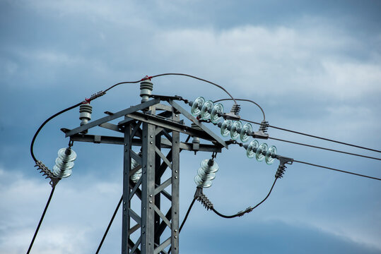 Close-up of glass insulators and high voltage power lines on an electricity pylon.
