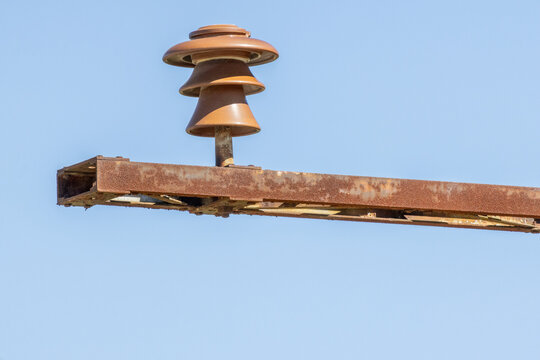 Rusty electrical insulator on power line against blue sky