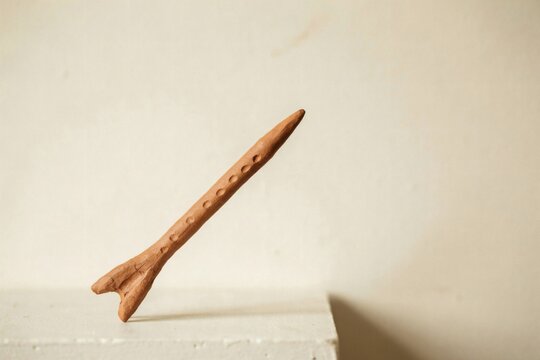Dimpled clay rod tilted over a white ledge in soft studio light