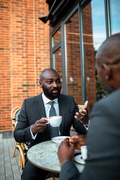 Two businessmen discussing over coffee at outdoor cafe