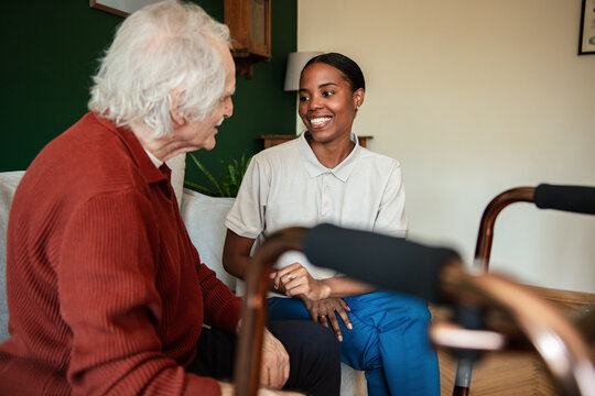 Smiling caregiver talking with senior man at home