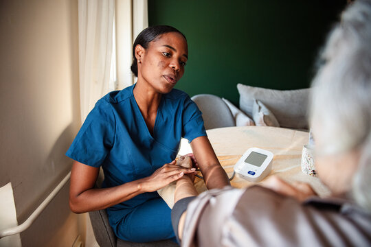 Nurse checking senior's blood pressure at home