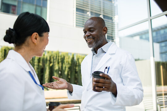 Two doctors chatting over coffee outside hospital