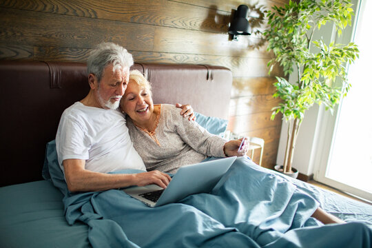 Senior couple online shopping in bed at home