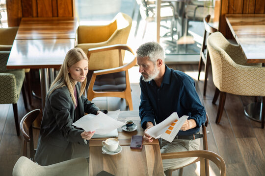 Two business professionals reviewing reports at a coffee shop