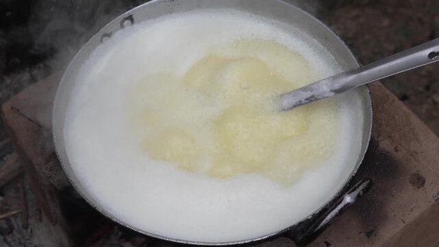 Boiling milk in a pan on a traditional brick stove with a ladle