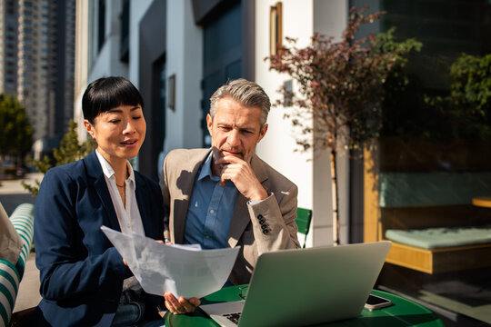 Two business professionals reviewing documents at outdoor cafe