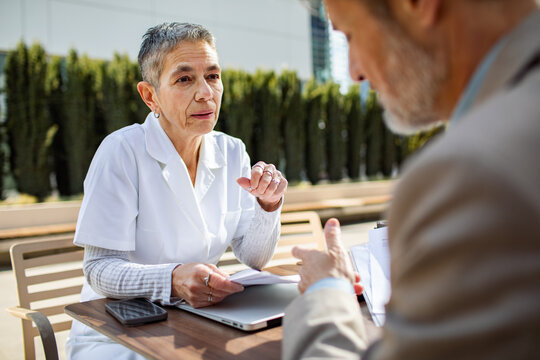 Nurse consulting senior patient at outdoor table