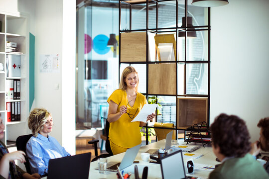 Smiling team leader presenting to colleagues in modern office