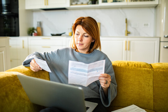 Woman paying household bills on laptop at home