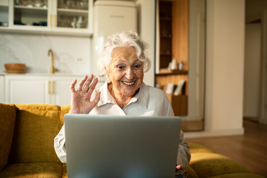Smiling senior woman waving during video call at home