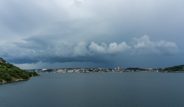 Sandnes cityscape along Gandsfjorden under dark storm clouds