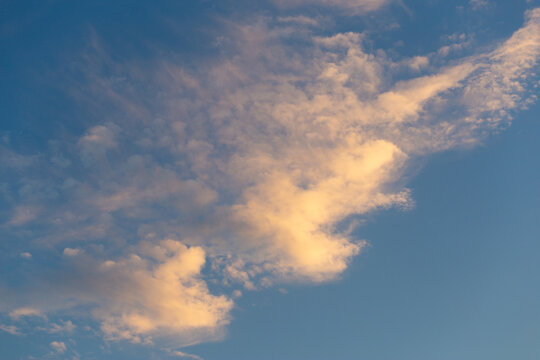 Soft fluffy clouds drifting across a clear blue sky, airy cloudscape, atmospheric texture, peaceful mood.
