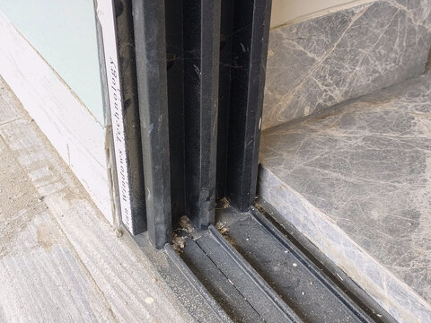 Detailed view of black aluminum sliding door frame base installed on grey marble floor