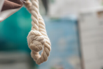 close-up photograph of a thick white cotton rope tied with a firm knot, set against a soft blurred background © awgraphoto