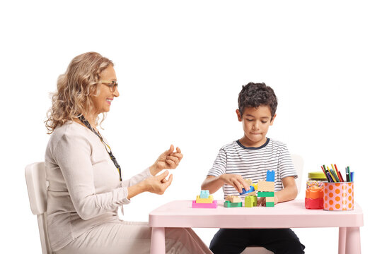 Older woman watching a boy building with plastic toy blocks