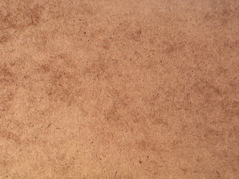 Close up texture of brown hardboard panel with natural wood fibers. Ideal background for carpentry, construction, craft design, recycled paper, mdf material, and industrial surface concepts