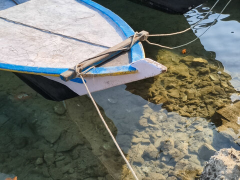Jakarta, Indonesia  September 6, 2026 Bow of a small wooden fishing boat tied with ropes in clear shallow sea water near the coast of Kepulauan Seribu.