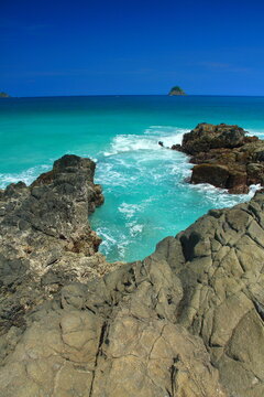 Turquoise tropical sea and waves breaking between rugged coastal rocks at Selong Belanak, Central Lombok, Indonesia.