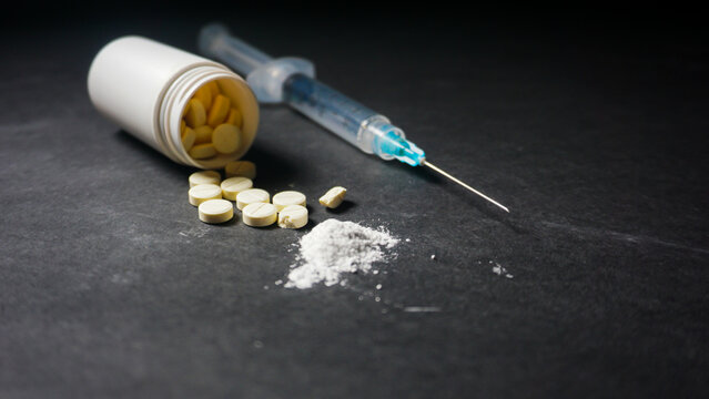 pills spilled from the bottle, white powder and a syringe with 3 mililiter size. Misused drugs concept. 